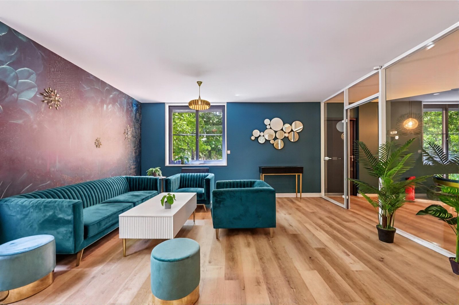 Salon du Garden : murs bleu canard, papier peint floral, canapés en velours, miroirs dorés, vue sur les arbres.